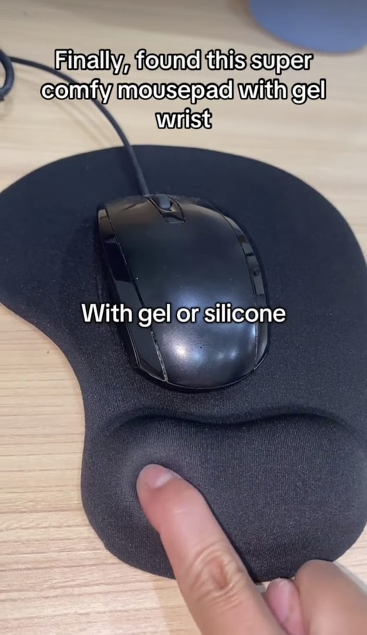 Hand resting on gel wrist mouse pad with laptop
